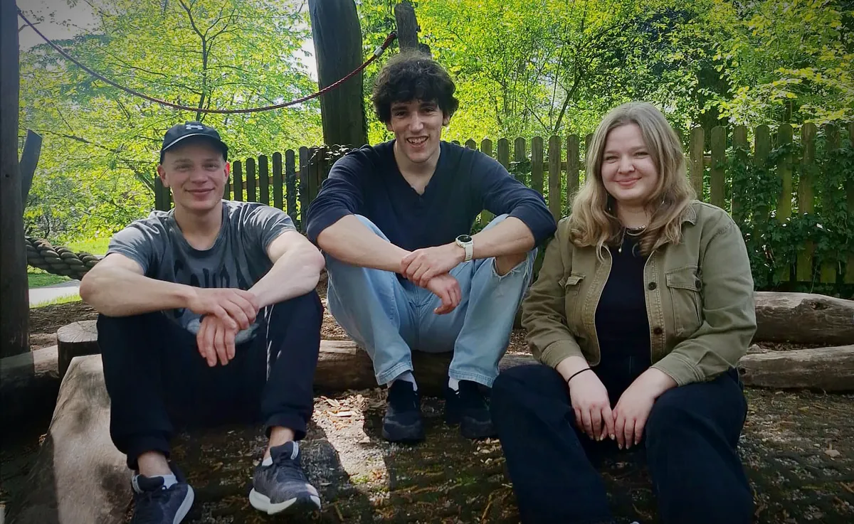The Cozy Cabbage Studio team — Sven, Heike, and Robin — sitting together in a leafy forest